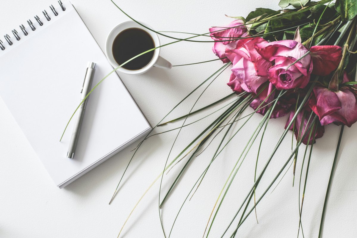 Support and Guidance A note pad and pen, a coffee cup, and a bouquet of pink roses